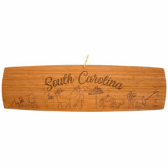 Photo of the South Carolina Extra-Large Charcuterie Board and Cheese Plate, featuring  laser-engraved artwork of the state name and images of  good 'ol beach days, iced tea and seafood