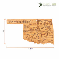 The Destination Oklahoma Cutting Board by Totally Bamboo is a bamboo-crafted piece shaped like the state of Oklahoma. It showcases laser-engraved artwork with illustrations and labels of cities and attractions, and features the Totally Bamboo logo in the top right corner. Its dimensions are 16-3/4 inches by 9 inches.