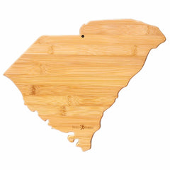 The Destination South Carolina Cutting Board by Totally Bamboo is a 14" x 11-1/2" cutting board crafted from bamboo and shaped like the state of South Carolina. It features a natural grain pattern and includes a small hole for hanging, offering a unique addition to your kitchen's cutting surface.