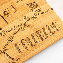 Explore the Totally Bamboo Destination Colorado Cutting Board, measuring 14-1/2" x 10-3/4". This state-shaped bamboo board beautifully showcases a hand-drawn map of regions in Colorado, complete with the state flag, roads, and towns such as Lamar, Las Animas, and La Junta. It also features a "Welcome to Colorful Colorado" sign—ideal as both a cutting surface and an eye-catching display piece.