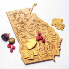 The Destination Georgia Cutting Board by Totally Bamboo, measuring 11-3/4" x 13-1/4", elegantly holds cheese, crackers, raspberries, and figs. It is crafted from bamboo and features laser engravings of city names and landmarks from Georgia.