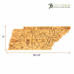 The Destination Tennessee Cutting Board by Totally Bamboo is a bamboo cutting board crafted in the shape of Tennessee, featuring engraved illustrations and city names. With dimensions of 18-1/2 inches wide and 7 inches tall, it proudly displays the "Totally Bamboo" logo in the top right corner.