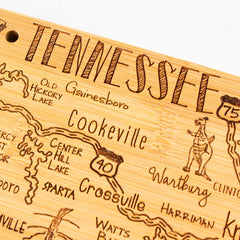 Explore the Totally Bamboo Destination Tennessee Cutting Board, measuring 18-1/2" x 7". This exquisite wooden map of Tennessee features laser-engraved artwork that beautifully highlights city names and landmarks. Handwritten styles emphasize locations such as Gainesboro, Cookeville, and Crossville, with charming illustrated animals and road symbols adding to the piece's intricate detail.