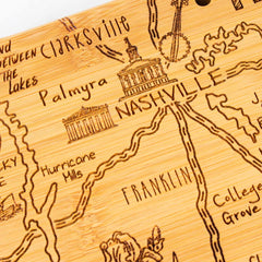 This unique Destination Tennessee Cutting Board by Totally Bamboo offers a detailed, close-up design of a wooden map showcasing Nashville, along with surrounding areas such as Clarksville, Palmyra, and Franklin. The laser-engraved artwork intricately highlights major roads and geographical features carved into the board's surface.