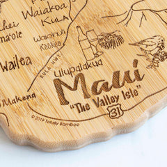 The Totally Bamboo Destination Maui Cutting Board, measuring 15-1/2" x 9-1/8", features a laser-engraved map highlighting the island's local landmarks, with scalloped edges and decorative elements such as text that reads "Maui The Valley Isle," along with pineapples and surfboards.