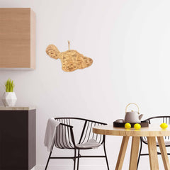 A contemporary dining space showcases a circular wooden table, two black chairs, and a teapot set. A geometric plant pot enhances the counter, while a laser-engraved Hawaii map from the Destination Series decorates one of the walls. Lemons add vibrant color to the Totally Bamboo Destination Maui Cutting Board that elegantly rests on the table.