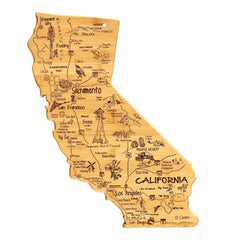 The Totally Bamboo Destination California Cutting Board, measuring 11" x 14-/4", is intricately shaped like the state and highlights major cities such as Los Angeles, San Francisco, and San Diego. It features playful laser-engraved artwork depicting landmarks like forests, deserts, and mountains with charming labels marking notable points of interest.