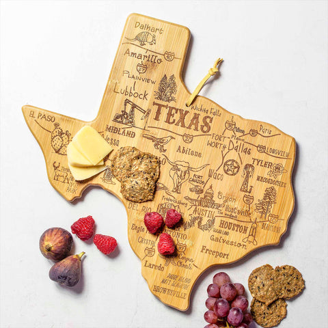 The Destination Texas Cutting Board by Totally Bamboo, measuring 14" x 13-3/8", is perfect for enhancing any Texas kitchen decor. It features engraved illustrations and city names and is beautifully arranged with slices of cheese, crackers, raspberries, figs, and grapes.