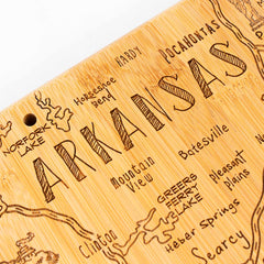 The Totally Bamboo Destination Arkansas Cutting Board, measuring 13" x 12", showcases a detailed map of Arkansas. It includes etched features of cities, lakes, and notable geographic locations with "Arkansas" prominently displayed at the center and "Horseshoe Bend" and "Batesville" nearby.