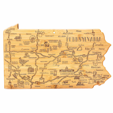 The Totally Bamboo Destination Pennsylvania Cutting Board, measuring 16" x 9-3/4", is crafted from wood and features a bamboo cutting surface. It is intricately laser-engraved with detailed map features, showcasing cities like Philadelphia and Pittsburgh and iconic symbols such as the Liberty Bell, along with other decorative elements.