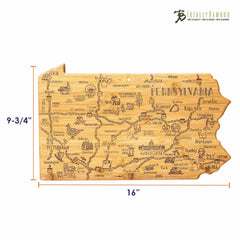 The Totally Bamboo Destination Pennsylvania Cutting Board features a distinctive shape representing Pennsylvania, complete with laser-engraved artwork of cities, landmarks, and highways. Measuring 16 inches wide and 9-3/4 inches tall, it includes logos and text at the top right corner.