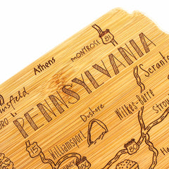 Crafted by Totally Bamboo, the Destination Pennsylvania Cutting Board, measuring 16" x 9-3/4", features a laser-engraved design that highlights city names such as Montrose, Athens, Dushore, and Williamsport. This piece from the Destination Series is adorned with artistic lettering and decorative road signs that enhance its appeal.