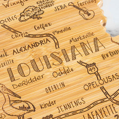 The Destination Louisiana Cutting Board from Totally Bamboo, measuring 13" x 12", beautifully combines artistry and functionality. It features a laser-engraved depiction of Louisiana's cities and roads, including Alexandria, Marksville, and Opelousas. Illustrated trees accentuate the Kisatchie National Forest on this state-shaped carved wooden map.