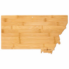 Introducing the Totally Bamboo Destination Montana Cutting Board, 16" x 9-1/2": a uniquely shaped bamboo cutting board designed to resemble the state of Montana. Featuring a light bamboo texture, it includes laser-engraved artwork and a small hole at the top for easy hanging.