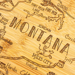 This beautifully crafted Destination Montana Cutting Board by Totally Bamboo features a laser-engraved rustic map of Montana, highlighting key locations such as Fort Peck Lake, Miles City, and Jordan. The board's decorative elements include a cowboy on horseback and stylish text carved with precision on the surface.