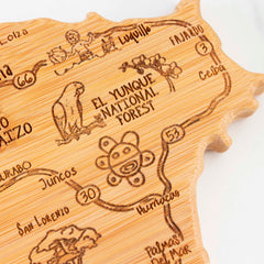 The Totally Bamboo Destination Puerto Rico Cutting Board, measuring 18" x 7", boasts an intricately engraved wooden map that highlights El Yunque National Forest, a parrot, and various towns connected by roads. Its artfully irregular border makes it a breathtaking charcuterie board perfect for your gatherings.