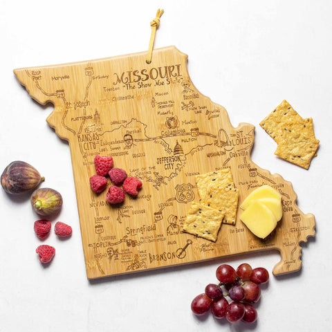 The Destination Missouri Cutting Board by Totally Bamboo, measuring 11-3/4" x 13-1/2", is a bamboo surface shaped like the state of Missouri and features laser engravings of iconic landmarks. It's perfect for stylishly presenting cheese, crackers, raspberries, grapes, and figs.