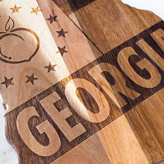 A beautifully crafted Rock & Branch® Origins Series Georgia Cutting Board by Totally Bamboo, featuring a laser-engraved artwork of the logo on an elegant acacia wood board.