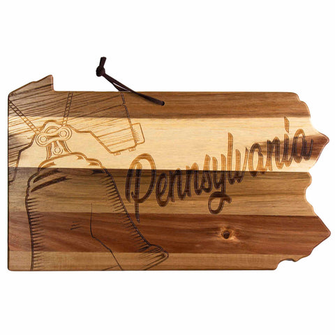 The Rock & Branch® Origins Series Pennsylvania Cutting Board by Totally Bamboo is crafted from acacia wood in the shape of Pennsylvania, featuring laser-engraved artwork of a bell and the word "Pennsylvania." It comes with a small rope loop for easy hanging.