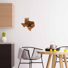 In a modern kitchen, the Rock & Branch® Origins Series Texas Cutting Board by Totally Bamboo adds charm with its acacia wood and laser-engraved design. A circular logo featuring a star enhances the atmosphere, while a round table with a teapot and lemons, black chairs, and geometric decor on the counter complete the look.