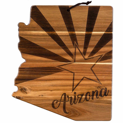 The Rock & Branch® Origins Series Arizona Cutting Board by Totally Bamboo is an acacia wood charcuterie board, artistically shaped like the state of Arizona. It features a star and sunburst design engraved on the surface, with "Arizona" elegantly inscribed in cursive at the bottom.