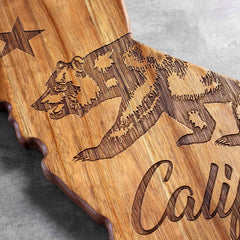 The Rock & Branch® Origins Series California Cutting Board by Totally Bamboo is a beautifully crafted charcuterie board made from rich acacia wood, featuring an elegant laser-engraved bear and star on its surface.