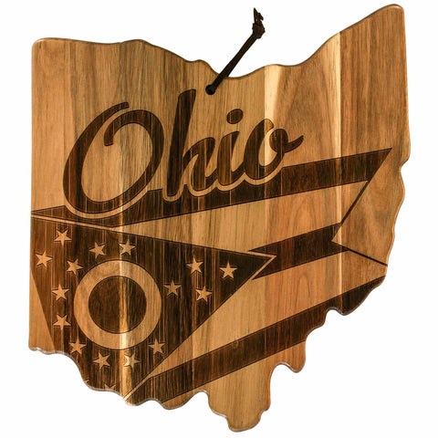 The Rock & Branch® Origins Series Ohio Cutting Board from Totally Bamboo is an acacia wood piece shaped like the state of Ohio. It showcases the word "Ohio" along with a stylized flag design featuring stars and a circular symbol, and includes a black strap for easy hanging.