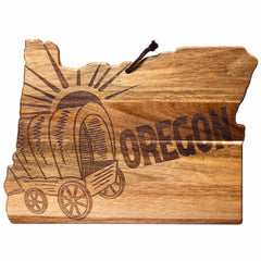 Introducing the Rock & Branch® Origins Series Oregon Cutting Board by Totally Bamboo, a unique acacia wood cutting board shaped like the state of Oregon. It features laser-engraved artwork of a covered wagon and sunburst design, with "OREGON" boldly etched across the surface.