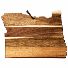 The Rock & Branch® Origins Series Oregon Cutting Board by Totally Bamboo is expertly crafted from rich acacia wood, displaying diverse shades of wood grain and designed in the shape of Oregon. It includes a leather loop for hanging and offers optional laser-engraved artwork for personalization.