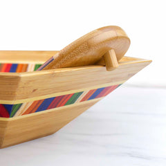 Introducing the Baltique® Marrakesh Collection Salad Bowl & Salad Hands Set from Totally Bamboo. This vibrant wooden bowl features a colorful striped pattern in shades of red, blue, green, and orange. The set is completed with matching salad hands that are perfect for serving your favorite dishes.