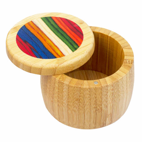 Introducing the Totally Bamboo Baltique® Marrakesh Collection Salt Cellar, an 8-ounce capacity cylindrical bamboo box showcasing a partially open lid adorned with vibrant stripes in red, orange, green, blue, and yellow. Its natural wood grain enhances the container's rustic charm.