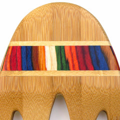 A detailed view showcases the textured elements of the Baltique® Marrakesh Collection Salad Serving Set, 11-3/4" by Totally Bamboo. It features a central stripe adorned with vibrant red, blue, green, orange, and white fibers. The bamboo wood is highlighted by its intricate grain patterns and smooth, curved design.