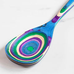 Part of the Baltique® Mumbai Collection by Totally Bamboo, this vibrant cooking spoon features a swirling design in green, purple, blue, and natural wood hues on colored birch. When placed against a white backdrop, its striking pattern offers an artistic flair.