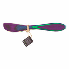 The Baltique® Mumbai Collection Spreader Knife, 8" by Totally Bamboo is a vibrant wooden utensil showcasing shades of purple, blue, and green. Crafted from smooth, rounded colored birch and tied with thin twine, it comes with a small black tag featuring white text.