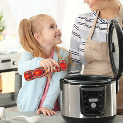 A young girl holding a vibrant utensil from the Totally Bamboo's Baltique® Marrakesh Collection smiles at a woman in an apron next to an open multicooker in a kitchen.