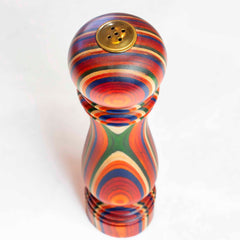 From the Marrakesh Collection by Totally Bamboo, this vibrant wooden salt shaker features a round top and uses refillable functionality. With swirling patterns in red, orange, yellow, green, and blue, it pops against a plain white backdrop.