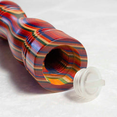 An up-close view of the Baltique® Marrakesh Collection Refillable Salt Shaker by Totally Bamboo showcases its vivid rainbow-striped wooden tube with a visible hollow interior. A white plastic cap is placed nearby, partially open and angled towards the viewer, enhancing the vibrant appeal of this unique design.