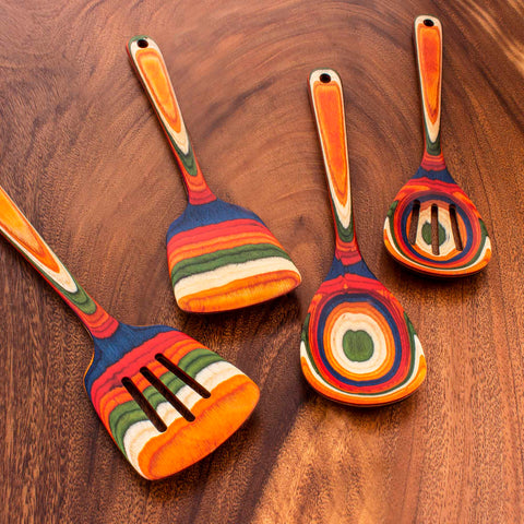 A 4-Piece Cooking Utensil Set from the Baltique® Marrakesh Collection by Totally Bamboo features an artful arrangement of colorful birch utensils on a wooden surface. These spatulas and spoons proudly display vibrant striped patterns in shades of orange, blue, green, and red.