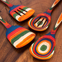 Explore the lively and colorful Baltique® Marrakesh Collection 4-Piece Cooking Utensil Set by Totally Bamboo. This set, made from birch, features two spoons and two slotted spatulas with vibrant layers of red, blue, green, orange, and white on a rich wooden backdrop.