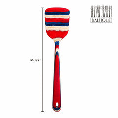 This vibrant Baltique® Old Glory Collection spatula by Totally Bamboo showcases a stars and stripes design in red, blue, and white patterns. The 12-1/2 inch spatula is crafted from colored birch and prominently features the "Baltique" logo along with a tree design in the top right corner.