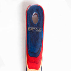 Close-up of the 12-1/2" spatula handle from the Totally Bamboo Baltique® Old Glory Collection, showcasing red, blue, and natural wood grain patterns. The handle has a small rounded hole near the top and is engraved with "BALTIQUE.