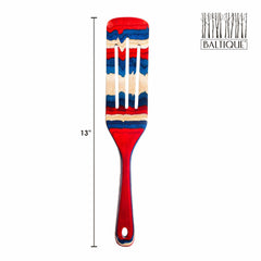 The Totally Bamboo Baltique® Old Glory Collection Spurtle, measuring 13 inches, showcases colorful stripes in shades of red, white, and blue. It features a "BALTIQUE" label accompanied by a tree design logo on the top right.