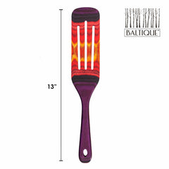 The Baltique® Waikiki Collection Spurtle from Totally Bamboo showcases a vibrant multicolor design in shades of purple, red, and orange. This 13-inch kitchen tool is safe for non-stick cookware and features a stylized tree graphic alongside the Baltique logo at the top right.