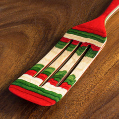 A 13-inch Baltique® North Pole Collection Spurtle from Totally Bamboo rests on a wooden surface, showcasing its festive colors with bold stripes of red, green, and natural wood tones. This vibrant kitchen tool adds a holiday touch to any culinary creation.