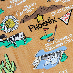 The Arizona Cutting Board with Artwork by Fish Kiss™ offers a delightful illustrated map of Arizona landmarks such as Camelback Mountain, Phoenix, and Scottsdale. Created by the brand Totally Bamboo, it enhances its charm with drawings of a golf course, cows, cacti, and New Cornelia Tailings Dam on a durable bamboo surface.