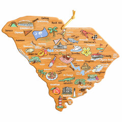 The South Carolina Cutting Board with Artwork by Fish Kiss™ from Totally Bamboo features a bamboo cutting surface shaped like the state of South Carolina, adorned with hand-drawn artwork depicting cities, landmarks, and symbols such as beaches, mountains, and peaches. Notable locations like Charleston and Columbia are highlighted, and it includes a hanging loop for added convenience.