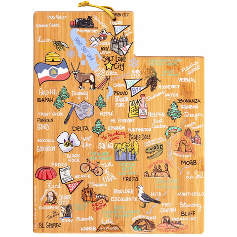 The Utah Cutting Board with Artwork by Fish Kiss™, crafted by Totally Bamboo, is designed in the shape of Utah and features vivid illustrations of cities, landmarks, and local icons like mountains and outdoor activities. It's a distinctive piece from a series of state-shaped cutting boards, equipped with a convenient yellow cord on the top-left corner.