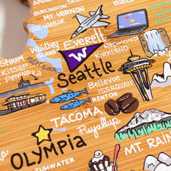 An artistic depiction of a map showcasing cities in Washington state, including Seattle, Tacoma, Olympia, and Everett. The design features icons such as the Space Needle, coffee beans, an airplane, and fish set against a wooden texture background similar to the Washington Cutting Board with Artwork by Fish Kiss™ from Totally Bamboo.