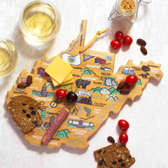 The West Virginia Cutting Board with Artwork by Fish Kiss™ from Totally Bamboo is a map-shaped wooden board that showcases illustrated landmarks and cities of West Virginia. It's perfect for serving cheese, crackers, cherry tomatoes, and salami. Accompanied by two glasses of white wine and a jar of breadsticks, this cutting board displays the charm of Fish Kiss artwork against a pristine white backdrop.