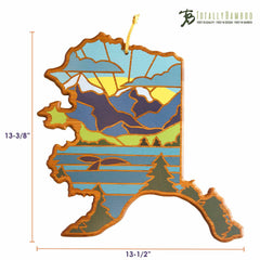 Introducing the Alaska Cutting Board with Artwork by Summer Stokes, a stunning piece shaped like the state of Alaska. It features a beautiful illustration of mountains, trees, and a sunset. Crafted by Totally Bamboo, this board measures 13-3/8 inches by 13-1/2 inches and proudly displays the brand's signature at the top.